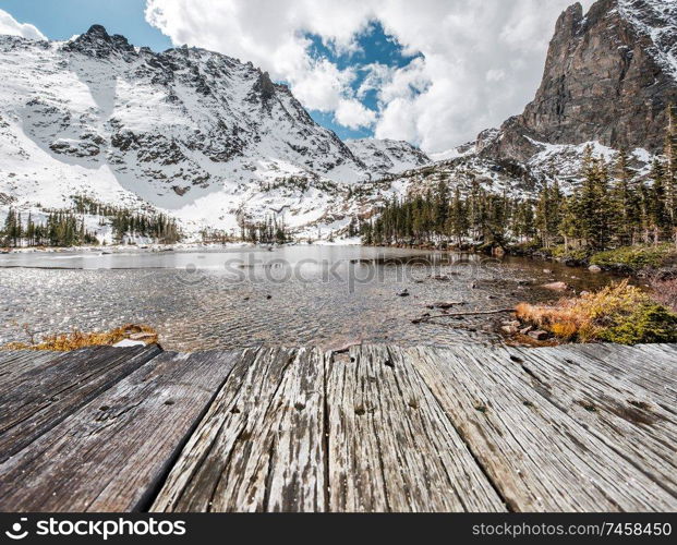 Lake Helene with rocks and mountains in snow around at autumn with cloudy sky. Rocky Mountain National Park in Colorado, USA. 