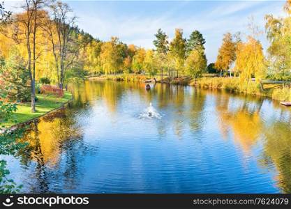 Lake in park with small house and autumn forest and trees