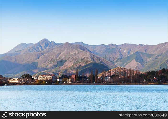 Lake Kawaguchiko blue water shore line with hotel buildings and moutains in beautiful winter - Japan