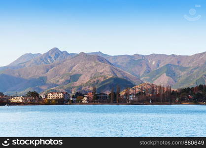 Lake Kawaguchiko blue water shore line with hotel buildings and moutains in beautiful winter - Japan