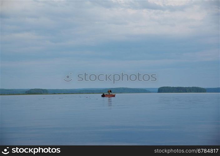 Lake Kenozero . Boat with fisherman on the water. Arkhangelsk region, Russia