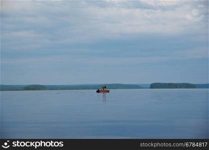 Lake Kenozero . Boat with fisherman on the water. Arkhangelsk region, Russia