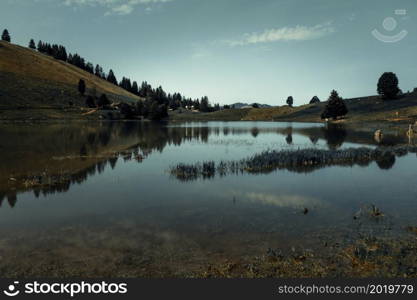 Lake of the Confins and Mountain landscape at sunrise. La Clusaz, Haute-savoie, France. Lake of the Confins and Mountain landscape at sunrise. La Clusaz, France