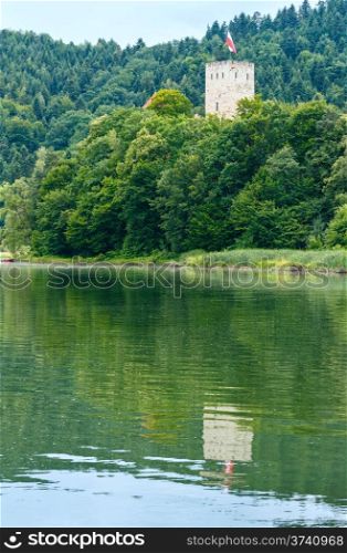 Lake (Poland) and tower above trees. Summer cloudy country view.