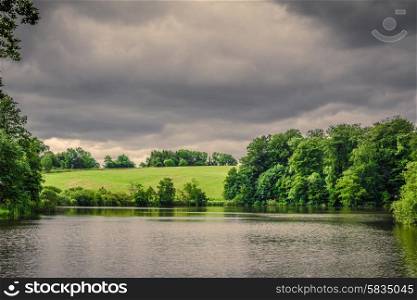 Lake scenery with green fields in dark cloudy weather