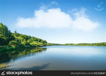 Lake scenery with green trees and blue sky