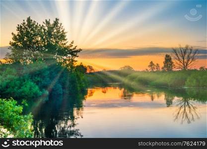 Lake water sunset and sun rays on nature landscape with sunset sky