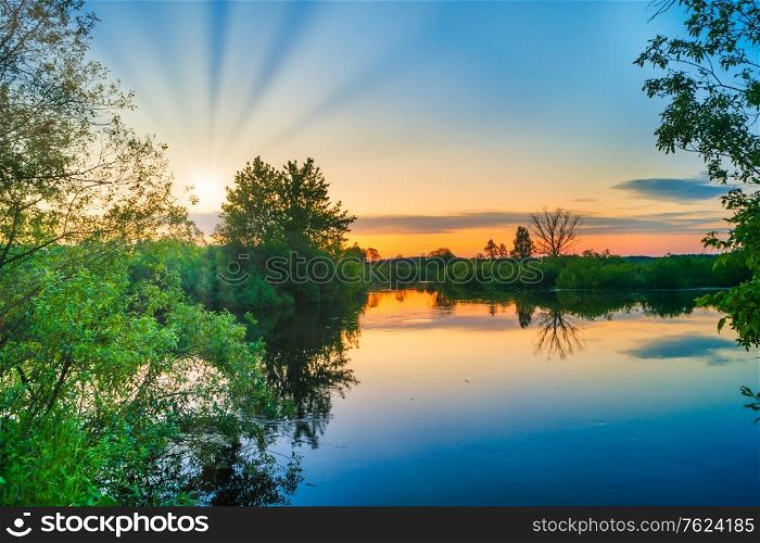 Lake water sunset and sun rays on nature landscape with sunset sky