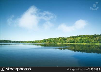 Lake with reflection of green trees in a forest