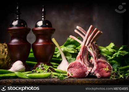 Lamb dish cooking with fresh lamb racks from butcher on dark rustic kitchen table at wooden background, top view