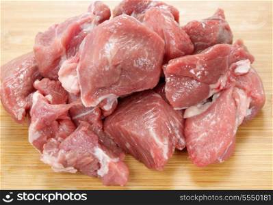 Lamb meat, chopped into rough cubes, on a wooden chopping board