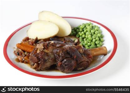 Lamb shanks braised with wine, onion, garlic, carrots, mushrooms and herbs, served with boiled jacket potatoes and green peas.