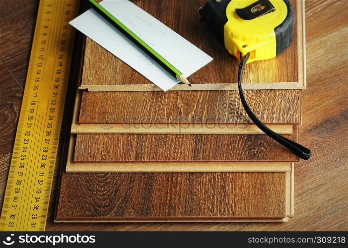 Laminate floor planks and tools on wooden background.. Laminate floor planks and tools on wooden background