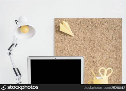 lamp laptop cork board against white wall