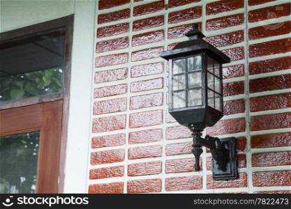 Lamp on the wall. Home painted red brick wall with black lamp.