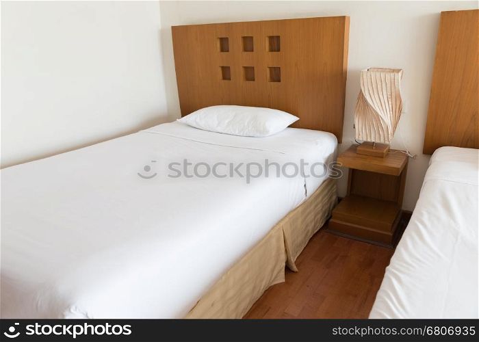 lamp, pillow and white bed in hotel room (selected focus)