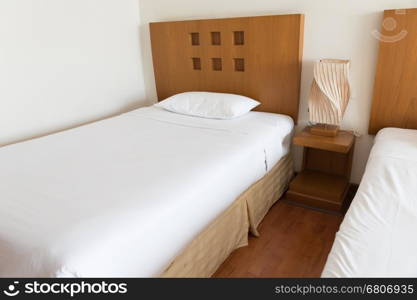 lamp, pillow and white bed in hotel room (selected focus)