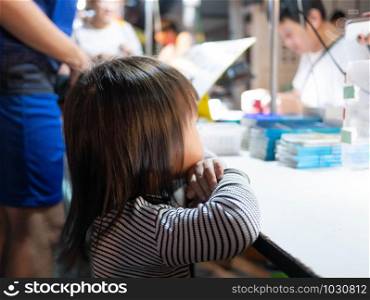 Lampang, Thailand; 5 October 2019 - Adorable Asian child girl stand to wait to buy foods at Kad Kong Ta Walking Street.