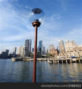 Lamppost in Sydney Cove with city skyline and water in Sydney, Australia.