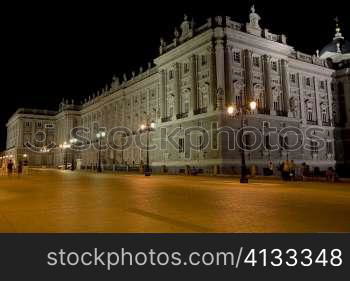 Lampposts lit up in front of a palace lit up at night, Madrid Royal Palace, Madrid, Spain