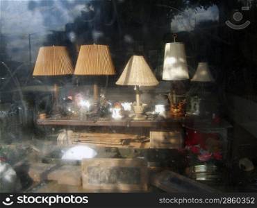 Lamps and other clutter in a dirty antique shop window, horizontal