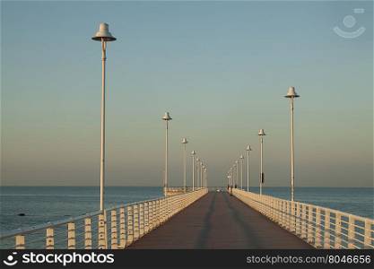 Lamps on the wharf. Sequence of lamps alternating with a sense of infinity of a marine pier of Marina of Massa