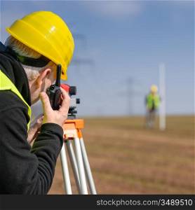 Land surveyors measuring land with tacheometer speaking through transmitter