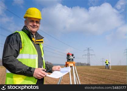 Land surveyors measuring with tacheometer wear reflective safety vest