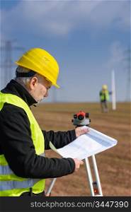 Land surveyors on construction site reading plans measure tacheometer