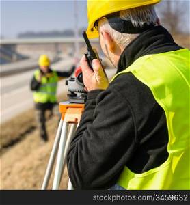 Land surveyors on highway measuring with theodolite