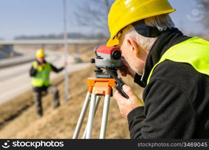 Land surveyors on highway measuring with theodolite