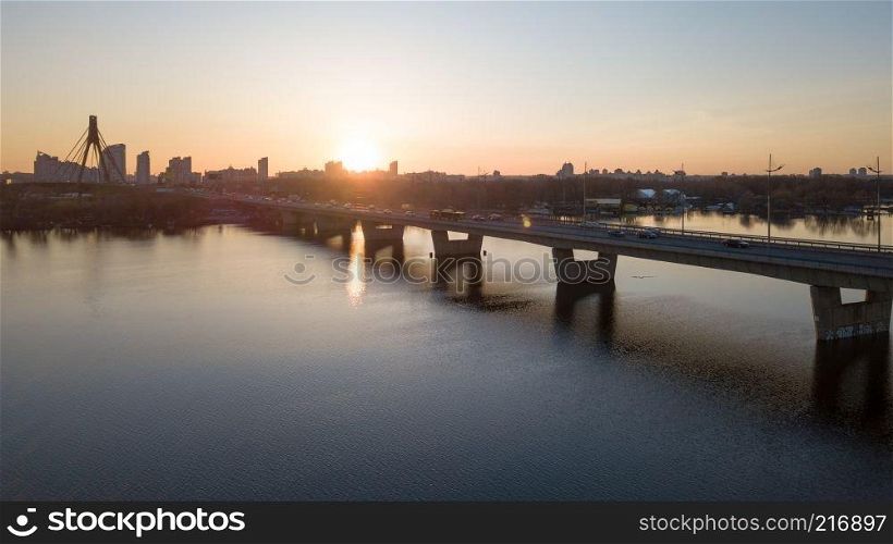 Landscape and sunset with suspension north Bridge across the Dnieper river, Obolon district in Kiev, Ukraine. Photo from the drone. Sunset of north bridge over the Dnieper River, Kiev.