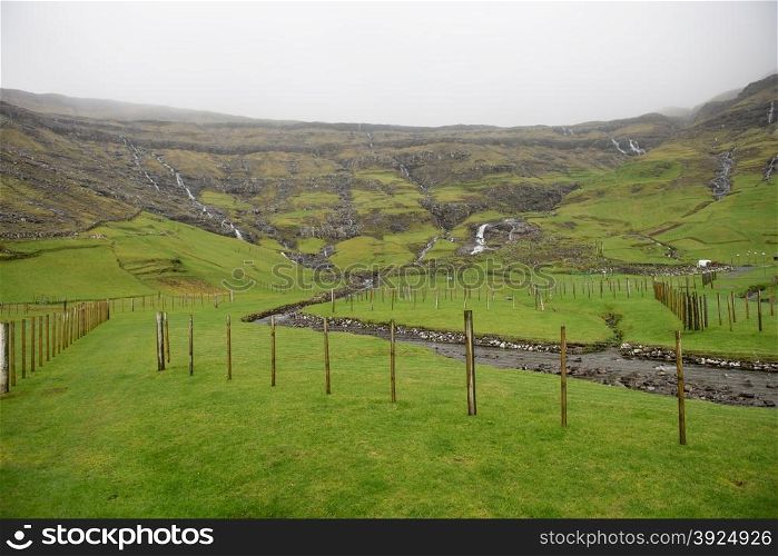 Landscape around Tjornuvik on the Faroe Islands with fences and mountain