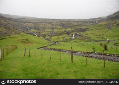 Landscape around Tjornuvik on the Faroe Islands with fences and mountain