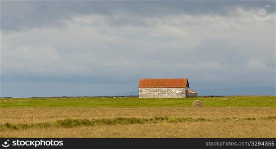 Landscape, farm building on the prairies, circular hay bale
