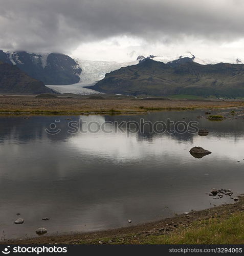 Landscape, glacier through mountain valley, reflected in glacial lake