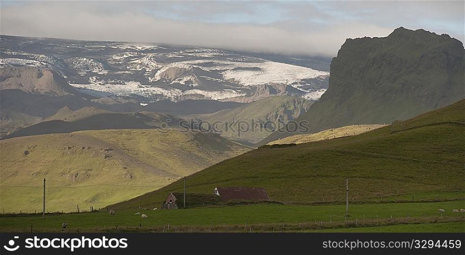 Landscape, glaciers, mountains and farmland, with barns