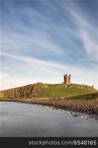 Landscape image of Dunstanburgh Castle on Northumberland coastli. Beautiful landscape image of Dunstanburgh Castle on Northumberland coastline in England during late Spring evening