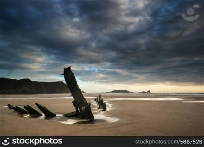 Landscape image of shipwreck on beach at sunset in Summer