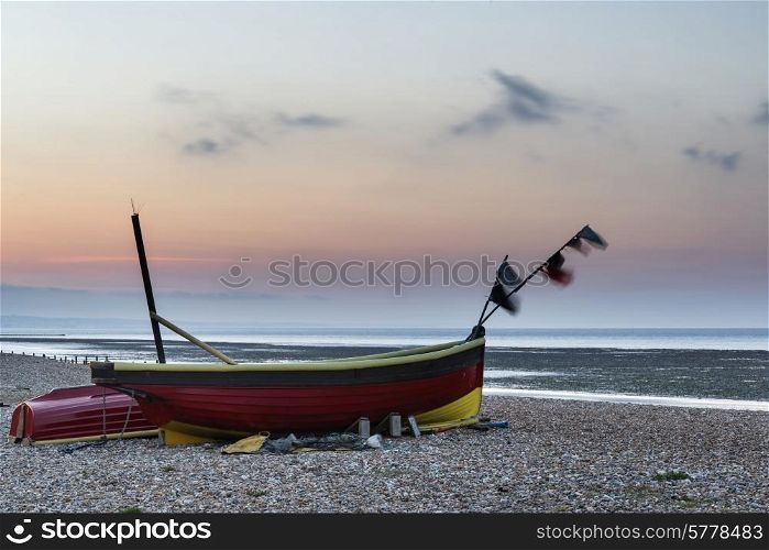 Landscape image of small fishing boats on beach at sunrise