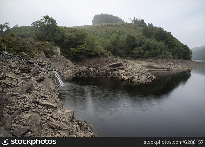 Landscape image of waterfall flowing into old abandoned quarry