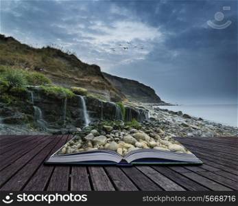 Landscape image of waterfall flowing onto rocky beach at sunrise conceptual book image