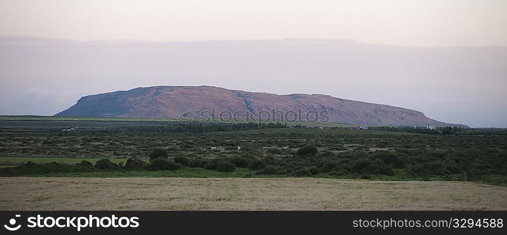 Landscape mountain range rising from grassland