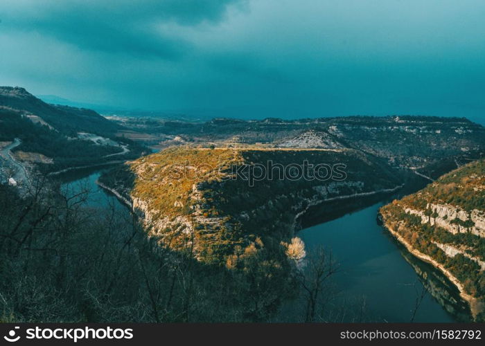 Landscape of a meander of a river at sunset on a cloudy day with sunbeams