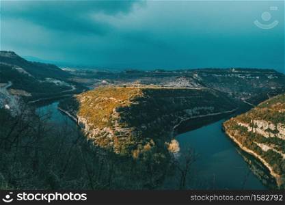 Landscape of a meander of a river at sunset on a cloudy day with sunbeams