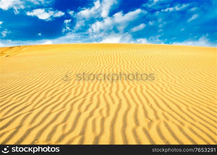 Landscape of desert sand dunes and blue sky with clouds over them