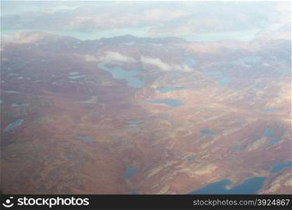Landscape of Greenland seen from the air in summer with rocky surface, lakes and ground moraine
