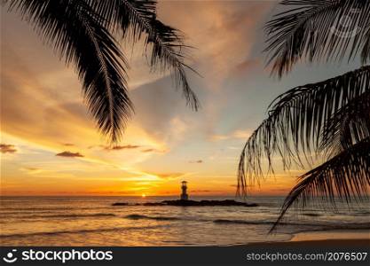 Landscape of Khaolak lighthouse with coconut leaf in the foreground and colorful sky in background