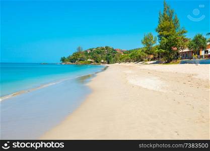 Landscape of long sand beach, clear sea and green trees at tropical island