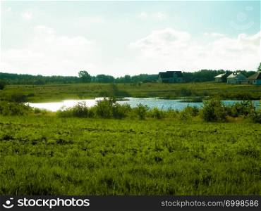 Landscape of meadow and pond in background. Summer season, polish nature, picture from Kashubian, Pomeranian Voivodeship.. Landscape of meadow and pond in background.